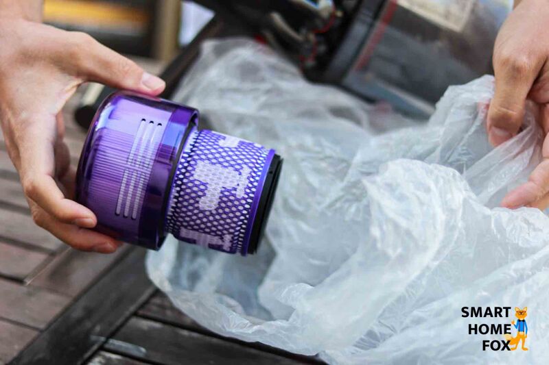 Filter des Akkustaubsaugers in der Tüte ausklopfen